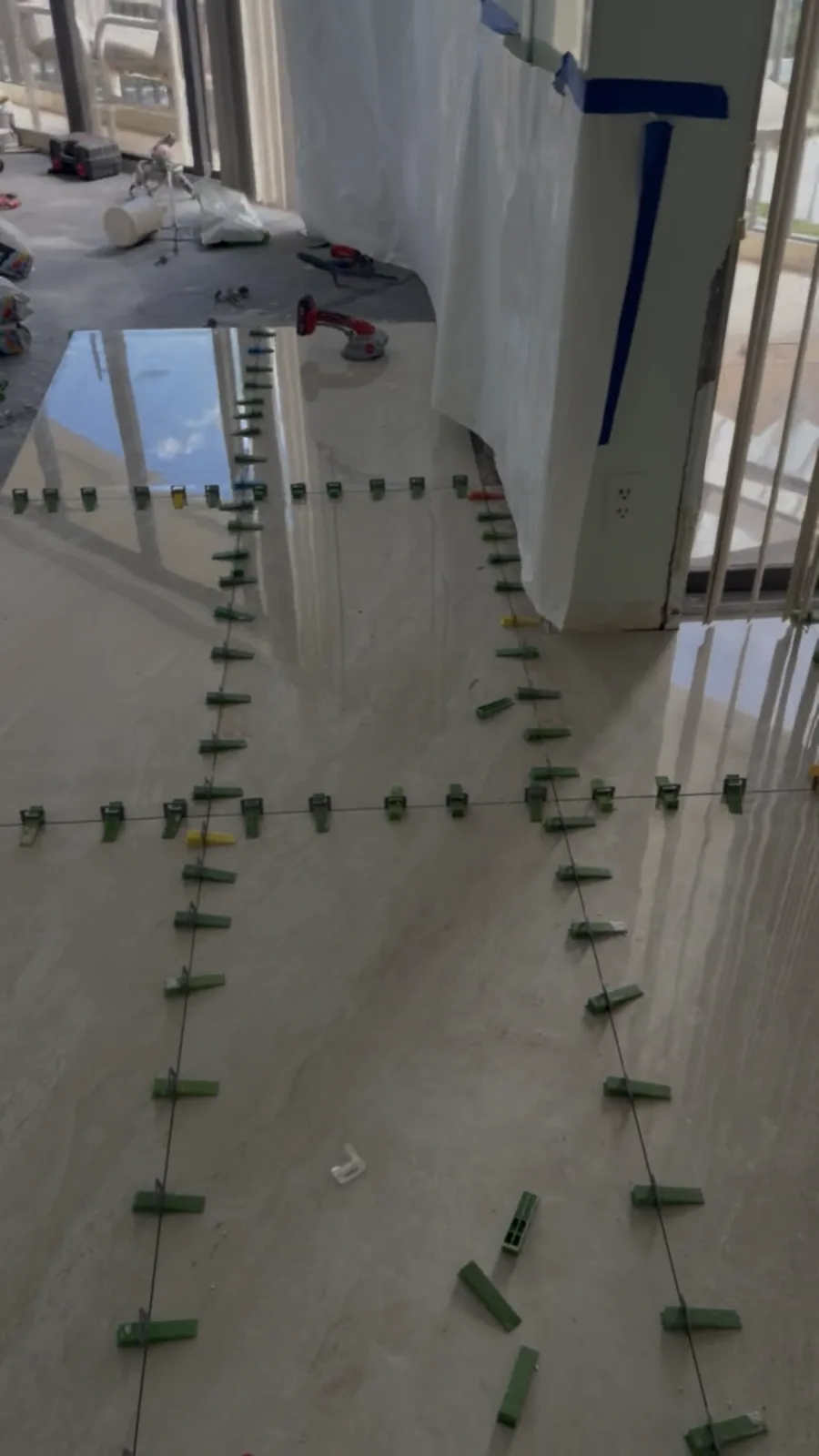 Polished large-format tile mid-installation with leveling clips in place